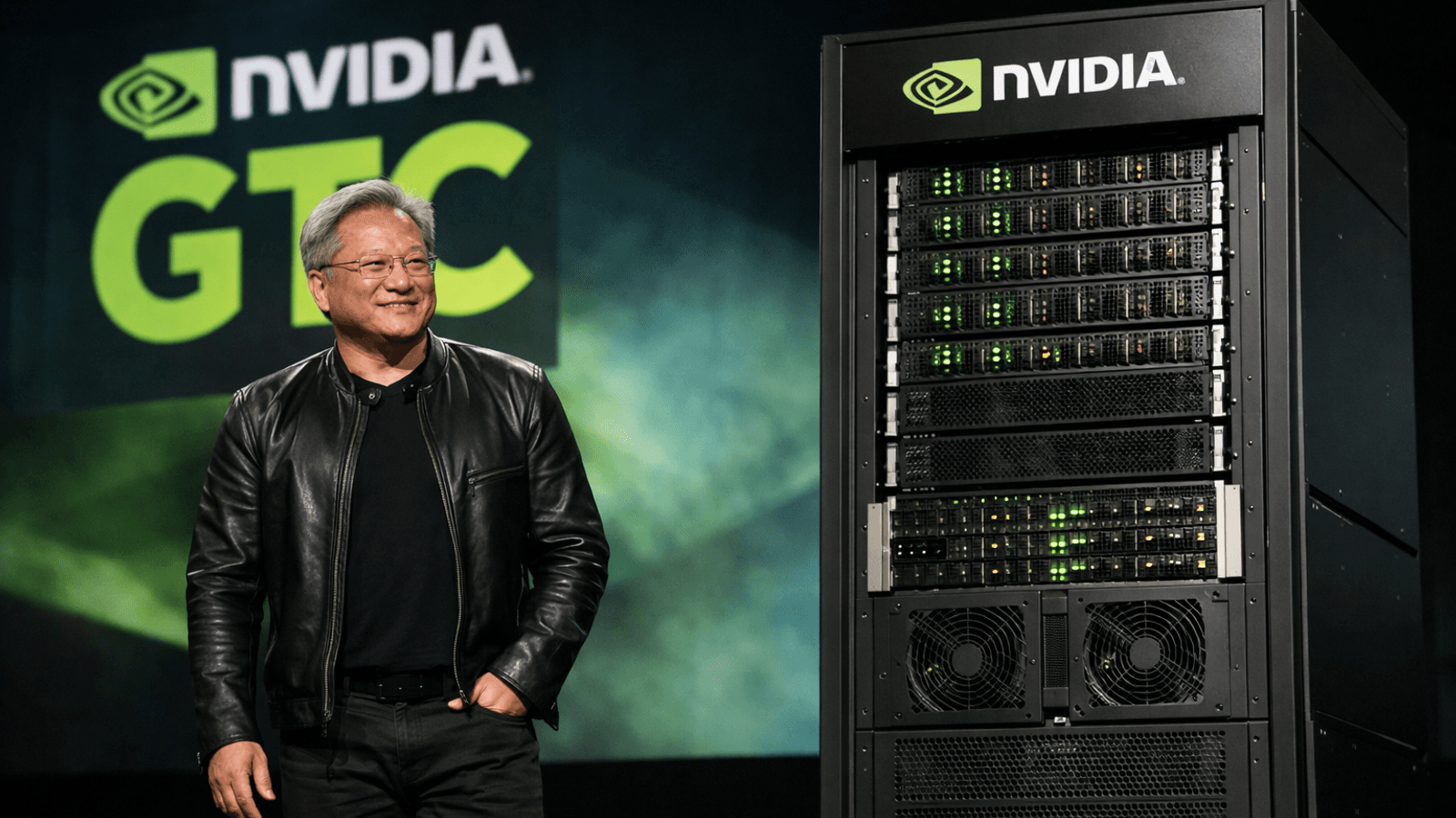 Jensen Huang on stage at Nvidia GTC beside a rack-scale AI server system during the company’s 2026 infrastructure announcements.