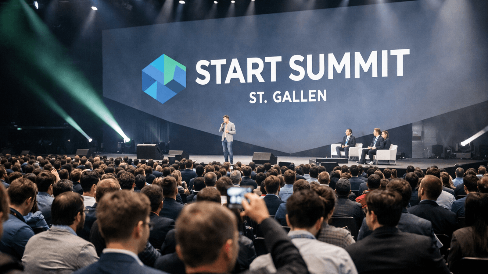 Crowds gather inside a large conference hall as speakers appear on stage during the Start Summit in St. Gallen.